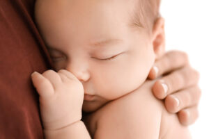 抱っこされて寝ている赤ちゃんの写真